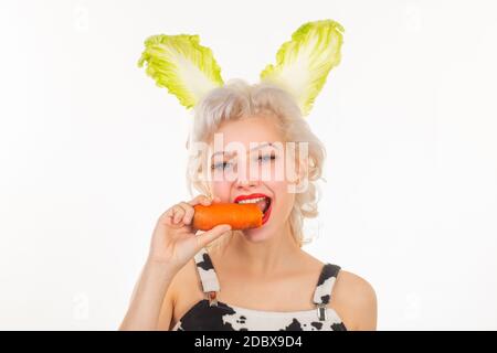 Überrascht Hase Frau essen Karotte. Frohe ostern und lustige ostertage. Junge Frau trägt Hasenohren am Ostertag. Stockfoto