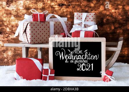 Tafel mit deutscher Kalligraphie Frohe Weihnachten und ein glückliches 2021 bedeutet Frohe Weihnachten und EIN glückliches 2021. Schlitten Mit Weihnachtsgeschenk Und Pr Stockfoto