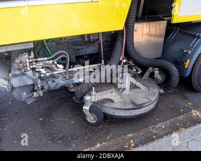 Ein Auto für die Reinigung von Straßen mit runden Bürsten auf einer Stadtstraße. Stockfoto