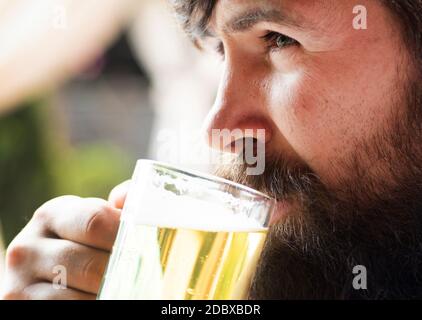 Porträt eines hübschen jungen Mannes, der ein Bier vom Fass probiert. Ein hübscher Barkeeper hält ein Pint Bier in der Hand. Stockfoto
