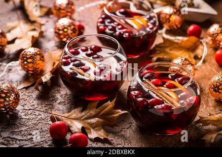 Glühwein mit Orange, Preiselbeeren, Zimt, Anis mit Herbstblättern und Weihnachtsbeleuchtung Stockfoto