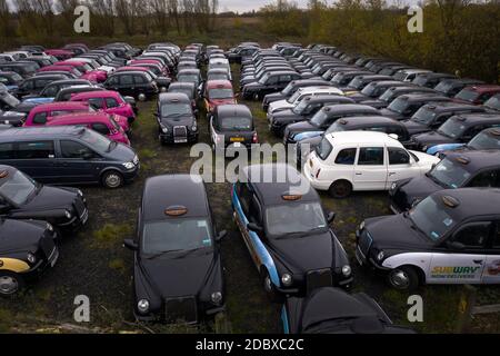 Ungenutzte schwarze Taxis in einem großen Bereich von Ackerland in Epping Forest geparkt, Die von GB Taxi Services gemietet wird, um ihre große Flotte von Londoner Taxis zu lagern, die aufgrund eines starken Nachfragerückgangs nicht mehr genutzt werden, da die Beschränkungen des Coronavirus weiterhin die Reise- und Büroarbeit reduzieren. Stockfoto