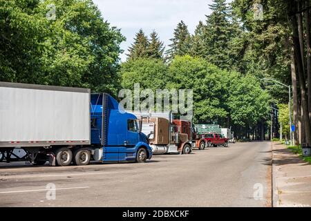 Verschiedene Marke und Modelle von großen Rigs semi-Trucks und Beladene Sattelanhänger stehen auf dem Parkplatz auf dem Rastplatz Grüner Wald für eine Pause und foll Stockfoto