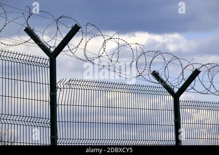 Zaun mit Stacheldraht auf dunkelblauem Himmel Hintergrund. Konzept der Freiheit Stockfoto