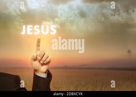 Geschäftsmann Hand zeigt Jesus Text mit einem Sonnenaufgang Himmel Hintergrund Stockfoto