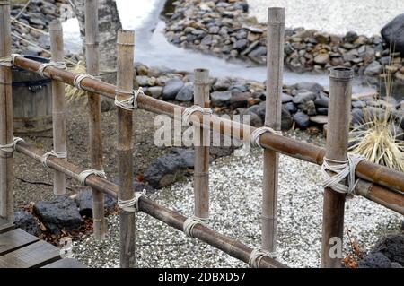 Bambuszaun mit Seilen in einem japanischen Garten gebunden Stockfoto