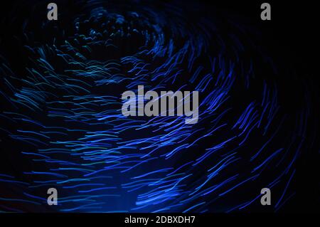 Eine abstrakte blaue Spirale aus verschwommenem Licht auf dunklem Hintergrund. Stockfoto