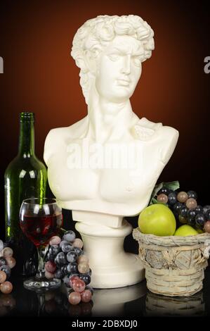 Ein römischer Kopf Büste eines Mannes, umgeben von Früchten und Wein mit einem Hintergrund. Stockfoto