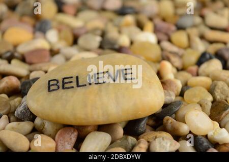 Ein Stein mit dem Wort glauben eingraviert auf ihm für Affirmation Zwecke. Stockfoto