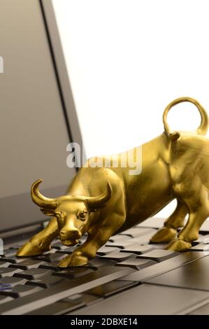 Ein Brass Bull und Laptop für Konzepte im Zusammenhang mit den Aufwärtstrends des Marktes. Stockfoto