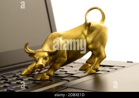 Ein Brass Bull und Laptop für Konzepte im Zusammenhang mit den Aufwärtstrends des Marktes. Stockfoto