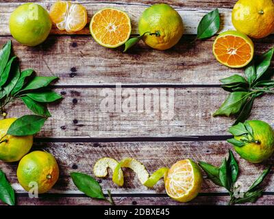 Grüne Mandarinen auf altem Holzhintergrund. Frische reife Hälfte, ganze und geschälte grüne Mandarinen mit Blättern, Draufsicht oder flache Lage. Platz für Text oder Design kopieren. Stockfoto