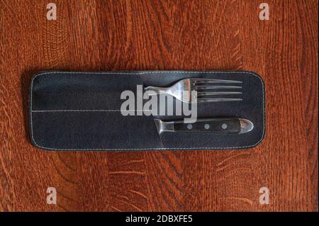 Restaurant Besteck eine Gabel und Messer in einem speziellen schwarz Lederetui liegen auf einer Holztischoberfläche Stockfoto