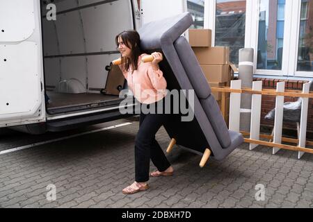 Frau Bewegt Neue Sofa-Möbel Aus Lkw Stockfoto