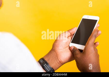 Nahaufnahme Asian glücklich Porträt jungen schwarzen Mann hält digitale mobile Smartphone leeren Bildschirm Platz auf den Händen, Studio isoliert auf gelbem Hintergrund Stockfoto