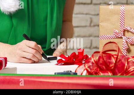 Frau unterzeichnet weihnachtsgeschenke mit einem schwarzen Stift. weihnachtsgeschenke Verpackung Stockfoto