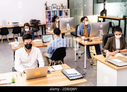 Gruppe von interracial Business Worker Team tragen schützende Gesichtsmaske in neuen normalen Büro mit sozialen Abstand Praxis mit Hand Desinfektionsmittel Alkohol Gel Stockfoto