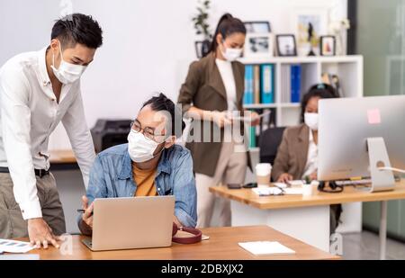 Gruppe von interracial Business Worker Team tragen schützende Gesichtsmaske in neuen normalen Büro mit sozialen Abstand Praxis mit Hand Desinfektionsmittel Alkohol Gel Stockfoto