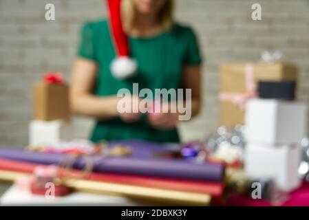 Hintergrund mit Unschärfe-Unschärfe. Geschenkverpackung für Weihnachten und Neujahr. Handmade. Mädchen Hände mit Geschenkband, Garn, Band und Geschenk verpackt Stockfoto
