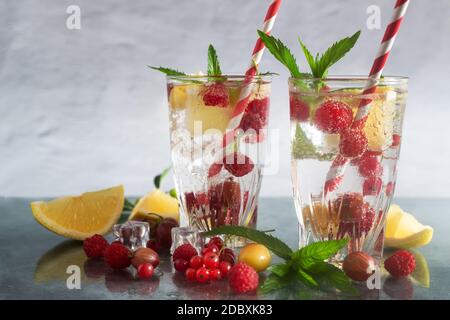 Erfrischender Cocktail aus natürlichen Früchten und verschiedenen Beeren mit Eis und Minzblättern, die mit Wasser durchtrinst sind. Enthält Zitrone, Himbeere, Kirsche, Gans Stockfoto