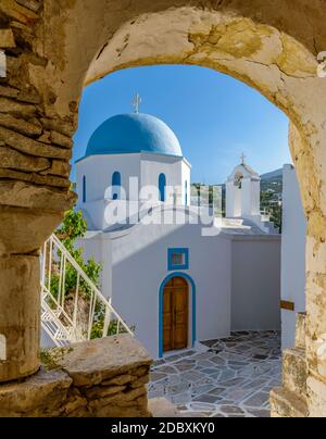 Traditionelle kykladitische Gasse mit einer schmalen Straße, weiß getünchten Häusern und einer Kirche mit einer blauen Kuppel auf der Insel lefkes Paros, Griechenland Stockfoto