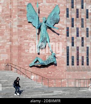 Eine Studentin steigt in der neuen christlichen Kathedrale in Coventry, England, unter die Skulptur von Jacob Epstein von St. Michael und dem Teufel. Stockfoto