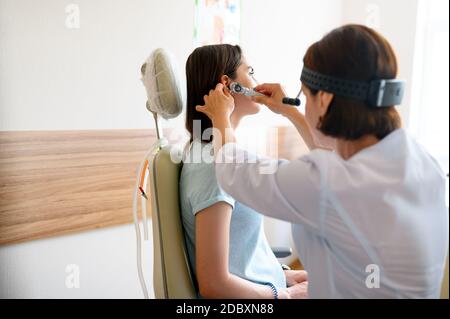Weibliche ent Arzt und Patient im Büro, Prüfung. Ohruntersuchung in der Klinik, professionelle Diagnostik. Medizinische Fachärztin und Frau im Krankenhaus, Kehlkopf Stockfoto