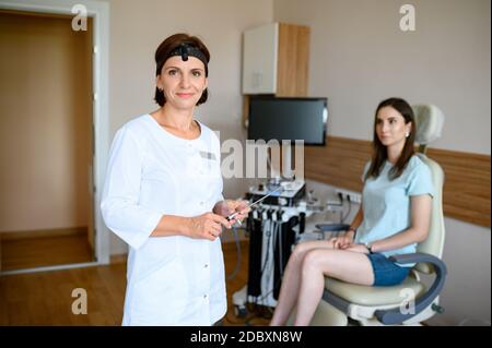 Lächelnde Kehlkopfärztin und Patientin im Stuhl. Ohr und Nase Untersuchung in der Klinik, professionelle Diagnostik, ent Arzt. Facharzt und Wom Stockfoto
