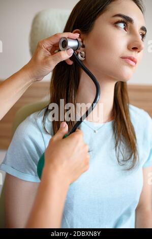 Kehlkopfärztin mit Otoskop und Patientin im Stuhl. Ohruntersuchung in der Klinik, professionelle Diagnostik, ent Arzt. Medizinische Fachkraft und Frau Stockfoto