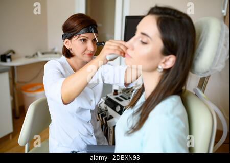 Weibliche ent Arzt und Patient im Büro, Prüfung. Ohruntersuchung in der Klinik, professionelle Diagnostik. Medizinische Fachärztin und Frau in Kehlkopfmediziner aus Stockfoto