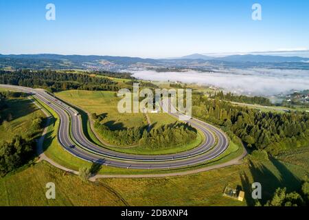 Polen. Kurvenreiche Rückweg von Krakau nach Zakopane, genannt Zakopianka, in der Nähe von Rabka und Chabowka. Luftaufnahme im Sonnenaufgangslicht mit Morgennebel. Fa Stockfoto