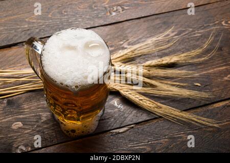 Draufsicht auf Bierpint mit Schaum auf Holztisch mit Ähren aus Weizen. Stockfoto