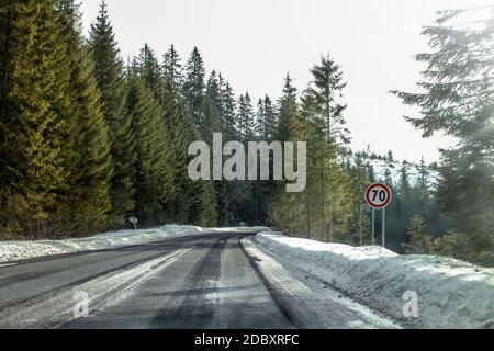 Blick von einem Auto reiten durch Straße Kurve im Winter mit 70 Tempolimit auf der rechten gefährlichen Fahrbedingungen. Stockfoto