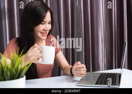 Arbeit von zu Hause, lächelnd Happy Asian Business junge schöne Frau sitzt auf dem Schreibtisch Arbeitsplatz Videokonferenz mit Team von Webcam Laptop comput Stockfoto