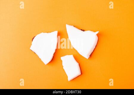 Happy Coconuts Tageskonzept, frische Kokosnuss Gruppe Stücke Scheiben, Studio Shot isoliert auf orangenen Hintergrund Stockfoto