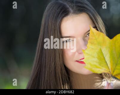 Porträt einer jungen schönen langhaarigen Brünette Frau mit Ahornblatt Stockfoto