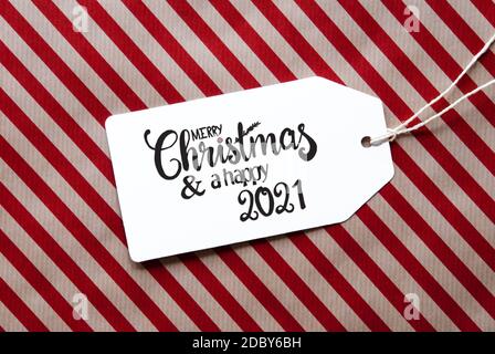 Label mit englischer Kalligraphie Frohe Weihnachten und EIN glückliches 2021. Rotes Geschenkpapier Als Hintergrund Stockfoto