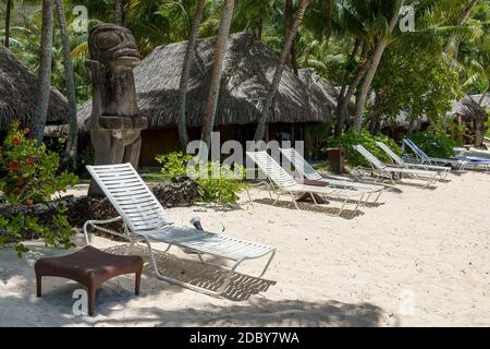 Polynesische Skulpturen und Liegestühle vor Bungalows, Marara Beach nahe Sofitel Hotel, Bora Bora, Französisch-Polynesien, Ozeanien Stockfoto