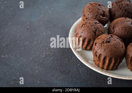 Teller voll mit Schokoladenmuffins auf dunklem Hintergrund. Köstliches Schokoladendessert. Speicherplatz kopieren. Stockfoto