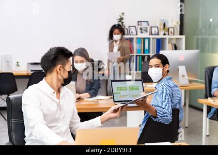 Gruppe von interracial Business Worker Team tragen schützende Gesichtsmaske in neuen normalen Büro mit sozialen Abstand Praxis mit Hand Desinfektionsmittel Alkohol Gel Stockfoto