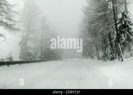 Blick von einem Auto reiten durch verschneite Winter, starker Schneefall, geringe Sichtbarkeit, Nebel und Dunst in Abstand - gefährliche Fahrsituationen. Stockfoto