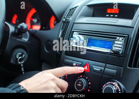 Auf Armaturenbrett Detail, man Finger Drücken des Not-Aus-Taste leuchtet während der Fahrt. Stockfoto