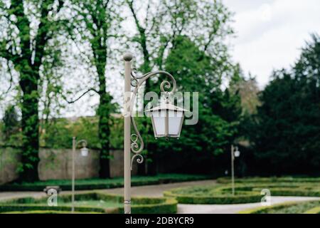 Nahaufnahme einer grauen Straßenlaterne im Park auf der Gasse. Stockfoto