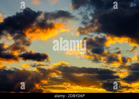 Ein sehr dramatischer Himmel voller Gelb, Blau und Orangen. Kontrastierende Wolken während des Sonnenuntergangs von der untergehenden Sonne beleuchtet. Hell gesättigt natürlich Stockfoto