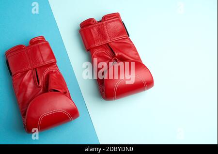 Paar rote Leder Boxhandschuhe auf blauem Hintergrund, flach liegend Stockfoto