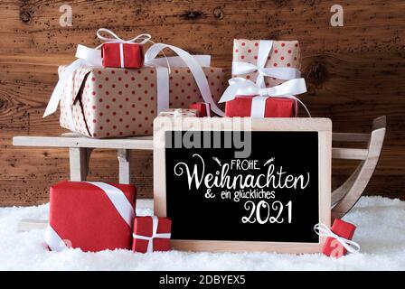 Tafel mit deutscher Kalligraphie Frohe Weihnachten und ein glückliches 2021 bedeutet Frohe Weihnachten und EIN glückliches 2021. Schlitten Mit Weihnachtsgeschenk Und Pr Stockfoto