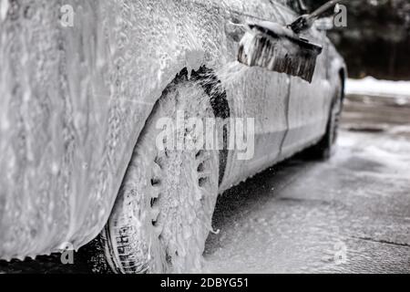 Auf dem Auto und Rad Detail, mit viel Seife, Bürste sprühen mehr Shampoo Schaum, wenn in der Waschstraße gewaschen. Stockfoto