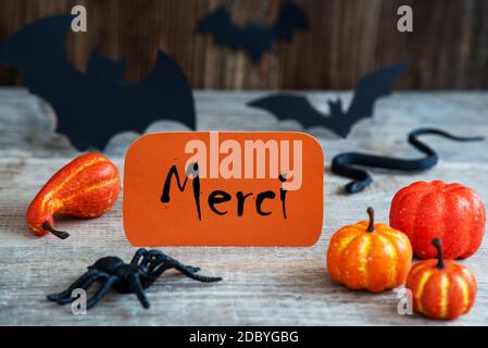 Orangefarbenes Etikett mit französischem Text Merci bedeutet Danke. Gruselige Halloween Dekoration Wie Fledermaus, Schlange Und Spinne Stockfoto