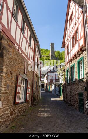 Schmale asphaltierte Straße in Monreal, Deutschland mit Löwenburg im Hintergrund Stockfoto