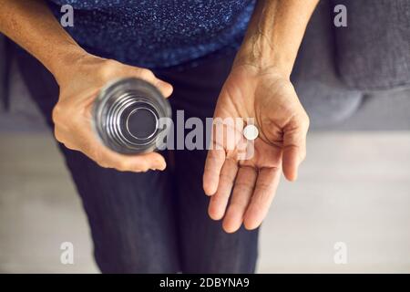Zugeschnittenes Bild Nahaufnahme einer löslichen weißen Pille und einem Glas Wasser in menschlichen Händen. Stockfoto
